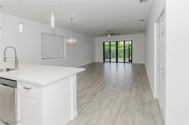 kitchen featuring light countertops, open floor plan, white cabinets, a sink, and dishwasher