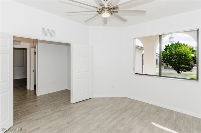 empty room featuring light wood-type flooring, ceiling fan, visible vents, and baseboards