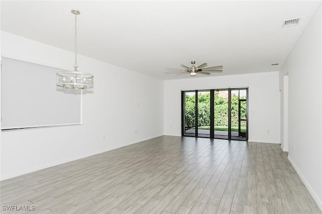 unfurnished room featuring visible vents, ceiling fan with notable chandelier, light wood-style flooring, and baseboards