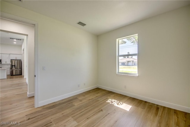 unfurnished room with visible vents, light wood-style flooring, and baseboards