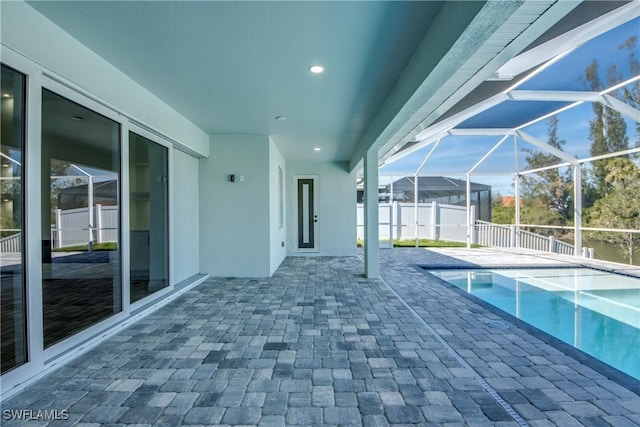 view of pool with a lanai, a patio, fence, and a jacuzzi