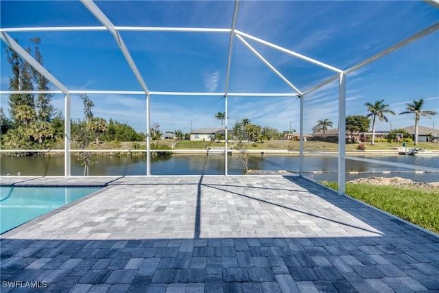 pool with a patio area, glass enclosure, and a water view