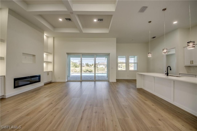 unfurnished living room with a glass covered fireplace, visible vents, a sink, and a high ceiling