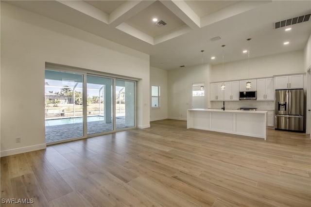 unfurnished living room featuring a high ceiling, coffered ceiling, light wood-style flooring, and visible vents