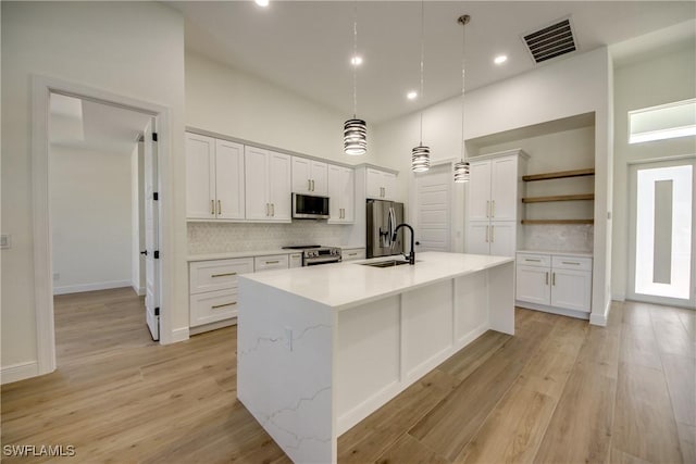 kitchen with stainless steel appliances, hanging light fixtures, open shelves, and white cabinetry