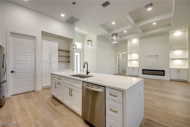 kitchen with decorative light fixtures, stainless steel appliances, white cabinetry, a sink, and an island with sink