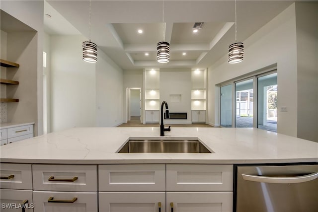 kitchen with a sink, white cabinetry, and light stone countertops