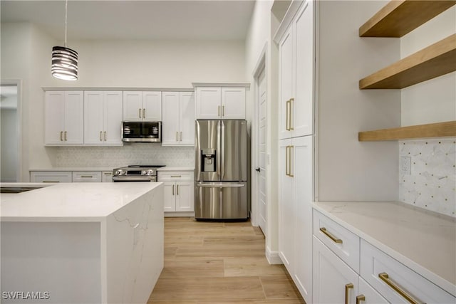 kitchen featuring light stone counters, stainless steel appliances, white cabinetry, hanging light fixtures, and open shelves