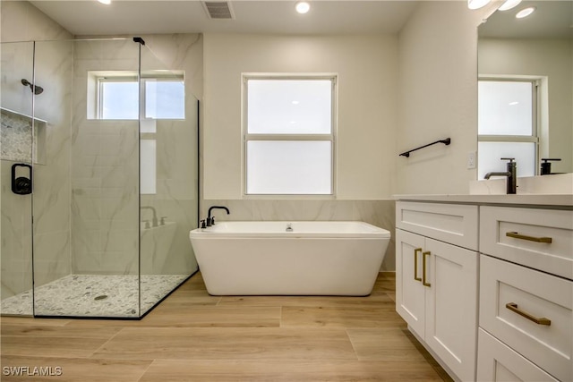 full bathroom with visible vents, vanity, a marble finish shower, and wood finished floors