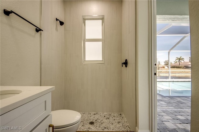 full bathroom with toilet, tiled shower, a wealth of natural light, and vanity