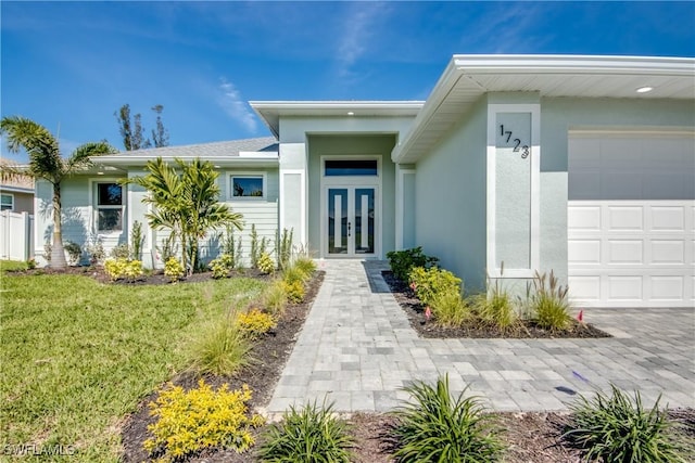 view of exterior entry featuring a garage, a yard, and stucco siding