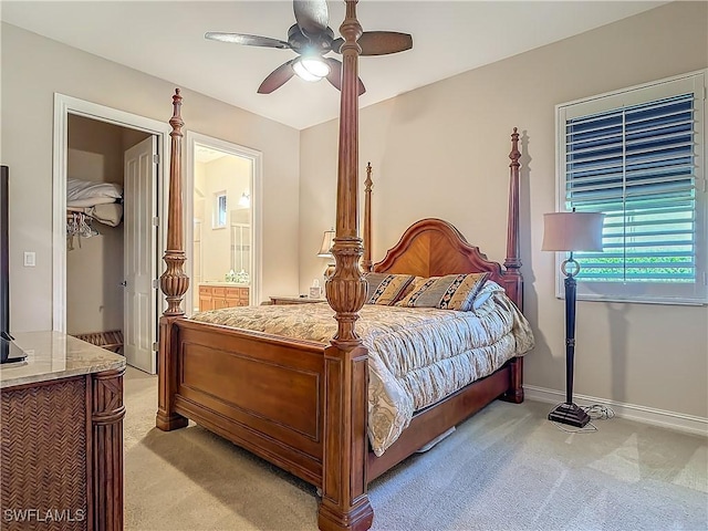 bedroom with baseboards, ensuite bathroom, a ceiling fan, and light colored carpet