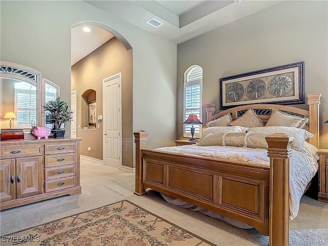 bedroom with arched walkways, light carpet, and visible vents