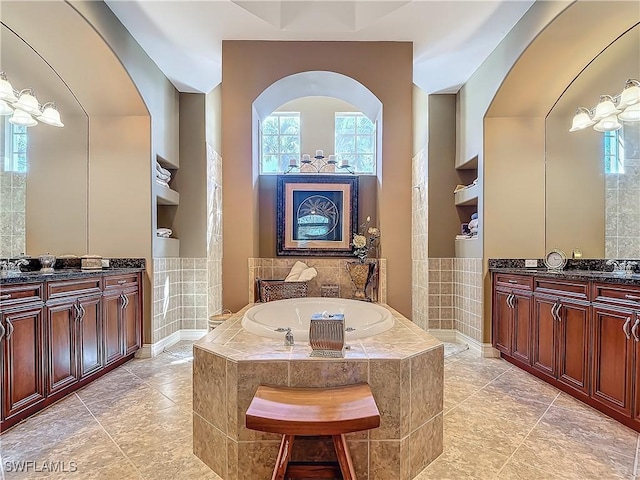 full bathroom with two vanities, a garden tub, and walk in shower