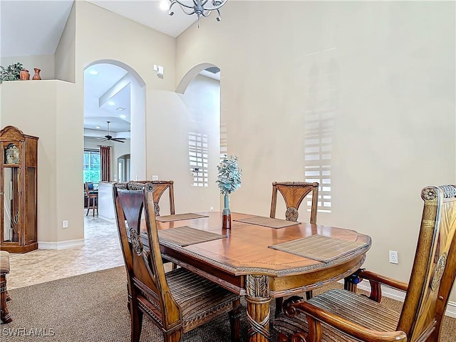 dining room featuring a ceiling fan, carpet, arched walkways, and baseboards