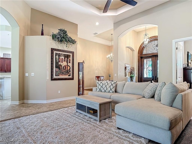 living area with arched walkways, a raised ceiling, visible vents, baseboards, and ceiling fan with notable chandelier