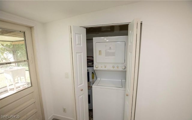 laundry room with laundry area, baseboards, and stacked washing maching and dryer