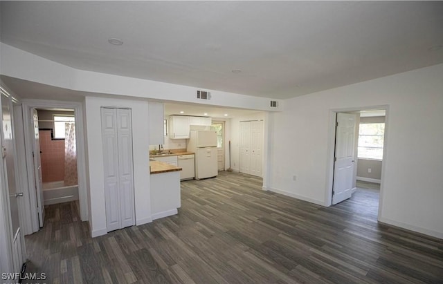 kitchen featuring white appliances, visible vents, white cabinets, and dark wood-type flooring