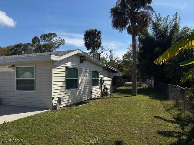 view of side of home with a patio, a lawn, and fence