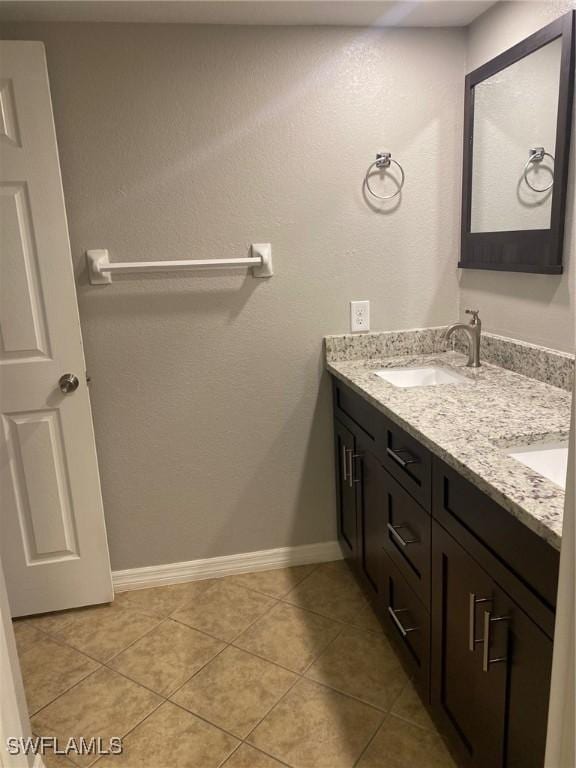 bathroom featuring double vanity, tile patterned flooring, baseboards, and a sink