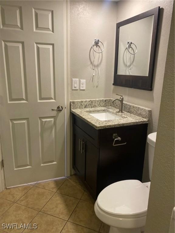 bathroom featuring toilet, tile patterned flooring, and vanity