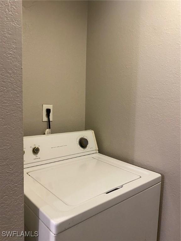 clothes washing area featuring washer / dryer, laundry area, and a textured wall