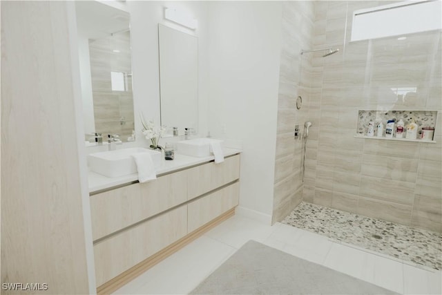 full bath featuring a tile shower, double vanity, a sink, and tile patterned flooring