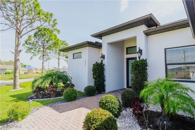 entrance to property with stucco siding and a yard