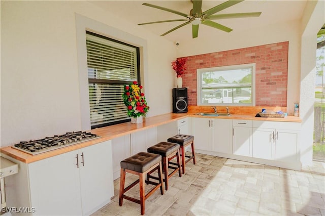 kitchen with a sink, gas stovetop, a ceiling fan, and white cabinets