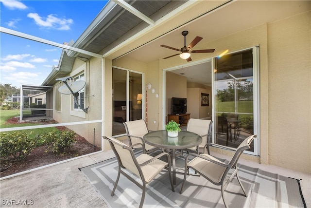 view of patio / terrace featuring outdoor dining space, glass enclosure, and ceiling fan