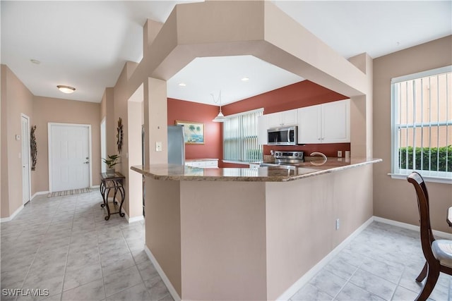 kitchen featuring pendant lighting, stainless steel appliances, white cabinetry, dark stone countertops, and a peninsula