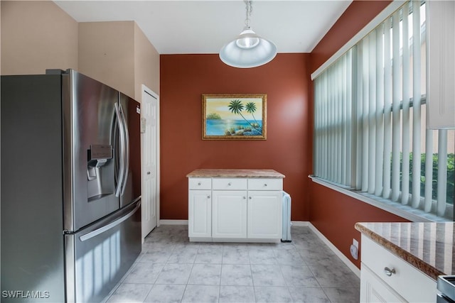 kitchen with baseboards, light stone countertops, pendant lighting, white cabinets, and stainless steel fridge
