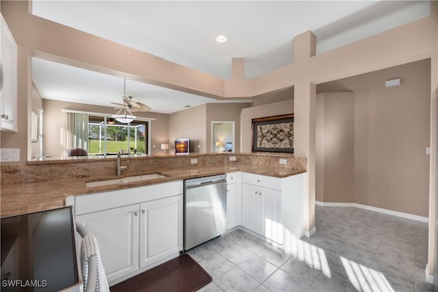 kitchen featuring a peninsula, dark stone counters, a sink, white cabinetry, and dishwasher