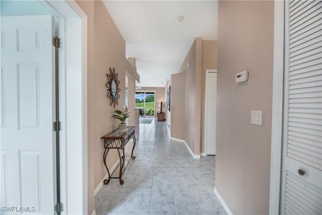 corridor featuring baseboards and light tile patterned floors