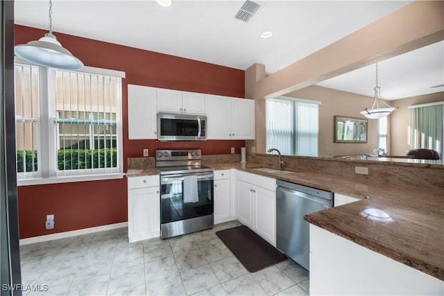 kitchen with visible vents, a sink, hanging light fixtures, stainless steel appliances, and white cabinetry