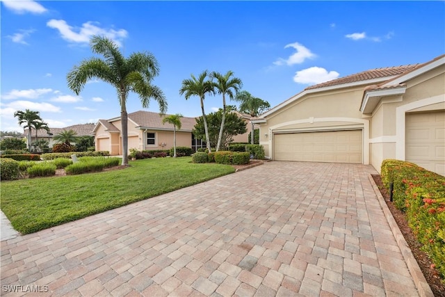 single story home with a garage, decorative driveway, a front yard, and stucco siding