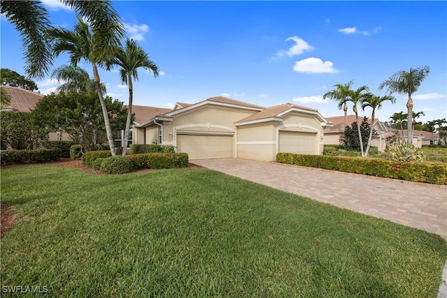 view of front facade with a front lawn, a tile roof, stucco siding, a garage, and driveway