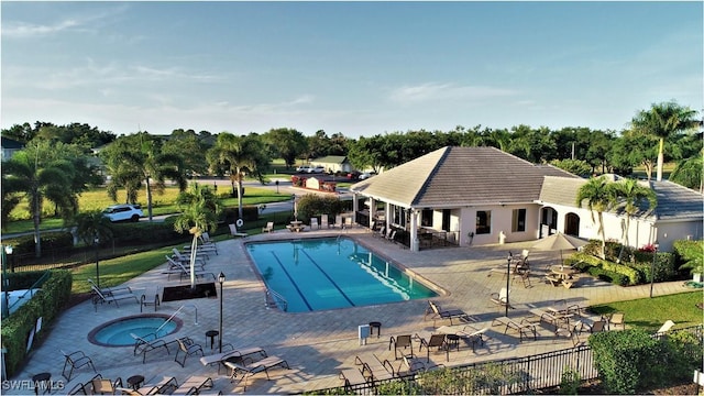 pool with fence, a hot tub, and a patio