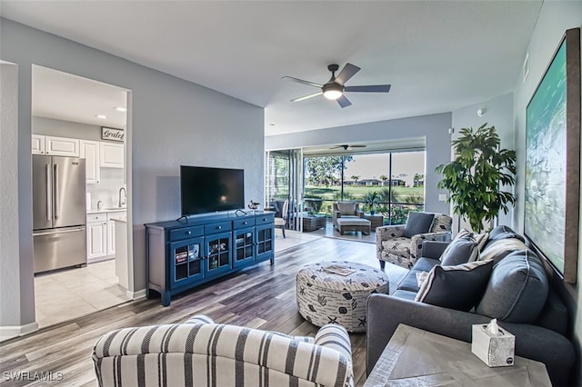 living room with light wood-style floors, baseboards, and a ceiling fan