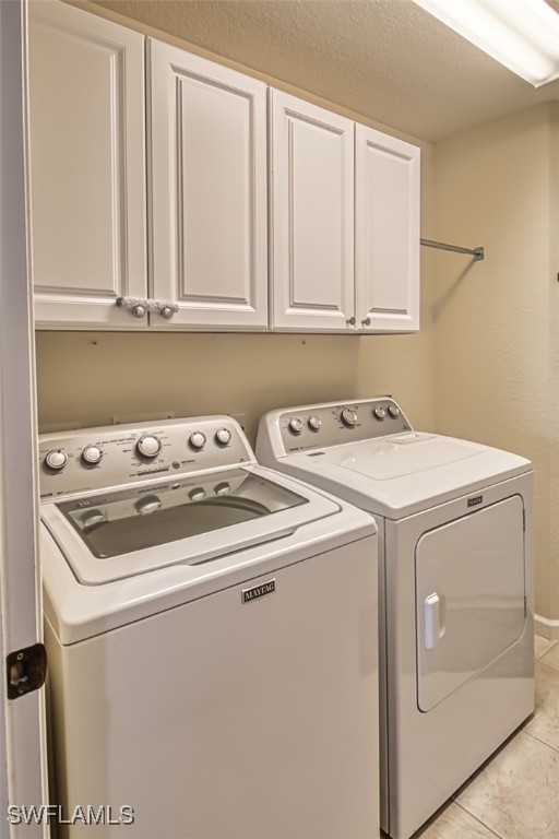 washroom featuring light tile patterned floors, washing machine and clothes dryer, and cabinet space