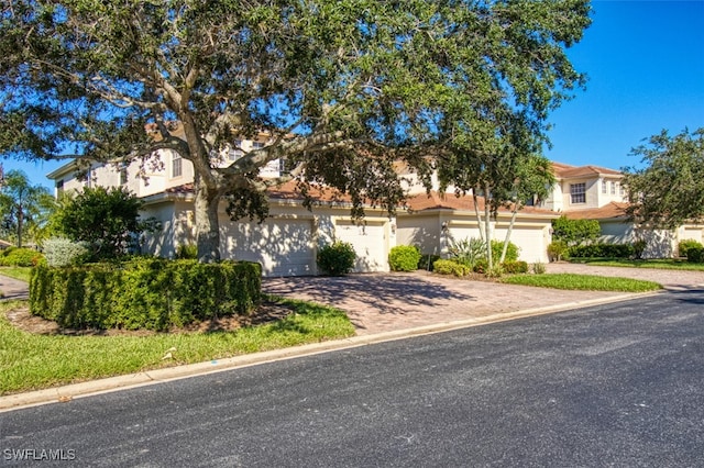 view of front of house with a residential view, decorative driveway, and stucco siding