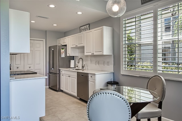 kitchen featuring stainless steel appliances, a sink, white cabinetry, light countertops, and tasteful backsplash