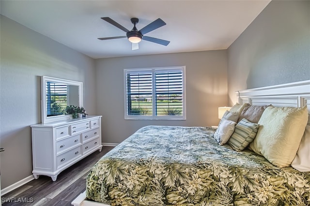 bedroom with ceiling fan, dark wood-type flooring, and baseboards