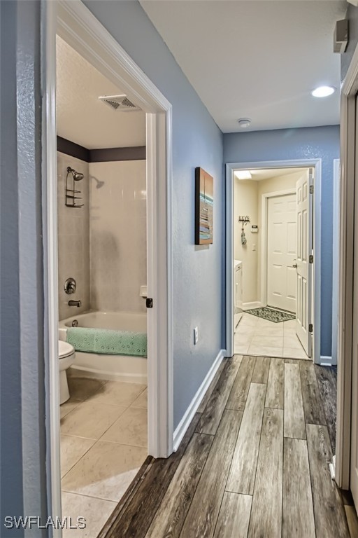 corridor with visible vents, baseboards, and wood finished floors