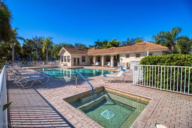 community pool featuring a community hot tub, a patio area, and fence