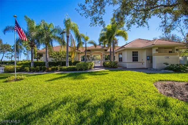 view of front of home with a tiled roof, a front lawn, and stucco siding