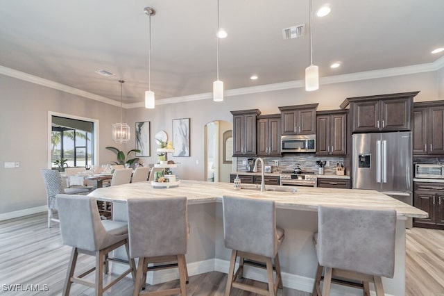 kitchen featuring a large island, appliances with stainless steel finishes, a kitchen breakfast bar, decorative light fixtures, and a sink