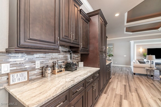 bar with light wood-type flooring, tasteful backsplash, baseboards, and crown molding