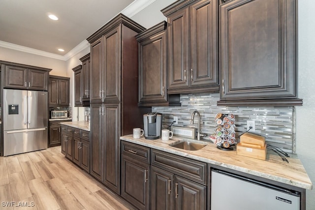 kitchen featuring crown molding, tasteful backsplash, appliances with stainless steel finishes, a sink, and dark brown cabinets