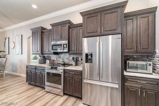 kitchen featuring a toaster, stainless steel appliances, baseboards, light wood-type flooring, and crown molding